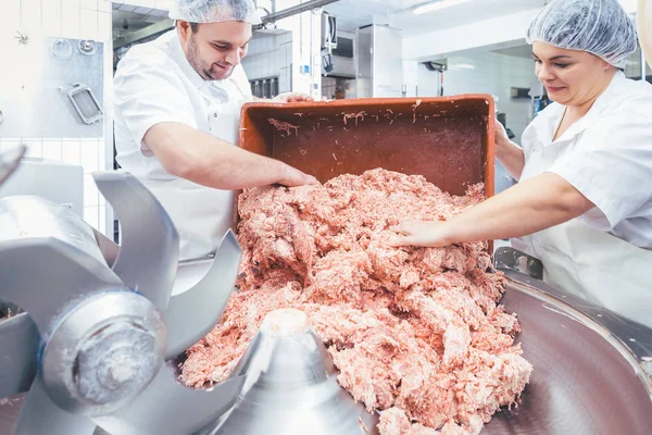 Team of butchers taking minded meat out of grinder — Stock Photo, Image