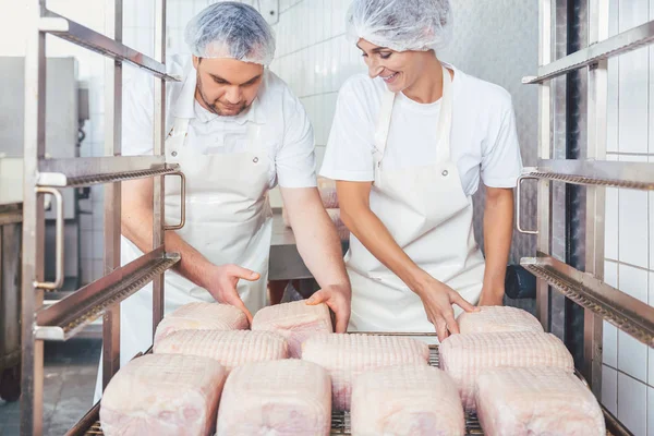 Carniceiro e mulher preparando carne para processamento posterior — Fotografia de Stock