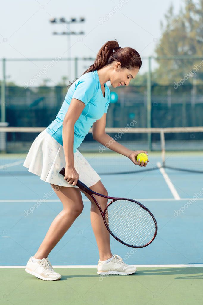 Professional female player smiling while serving during tennis match