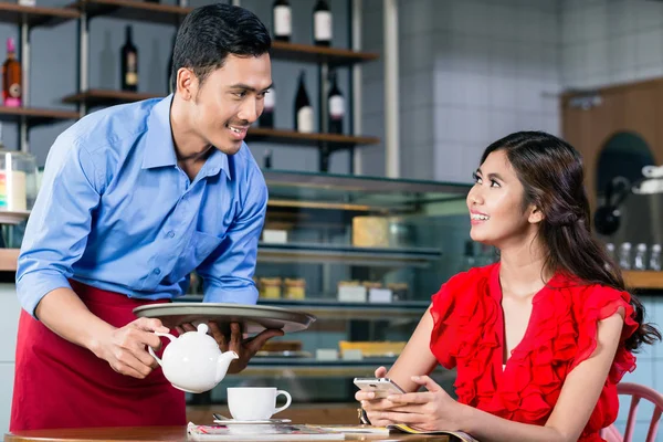 Όμορφος σερβιτόρος φλερτάρει με μια όμορφη γυναίκα, ενώ σερβίρει καφέ — Φωτογραφία Αρχείου
