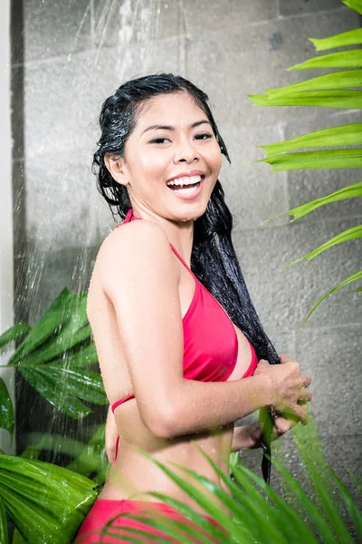 Asian woman using shower in tropical garden — Stock Photo, Image