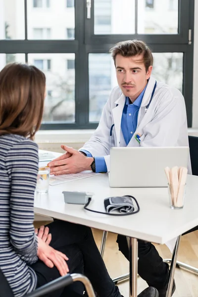 Giovane medico devoto che ascolta con attenzione il suo paziente durante la consultazione — Foto Stock
