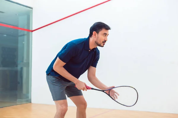 Raket profesyonel bir sahada oyun sırasında sahip genç squash oyuncu — Stok fotoğraf