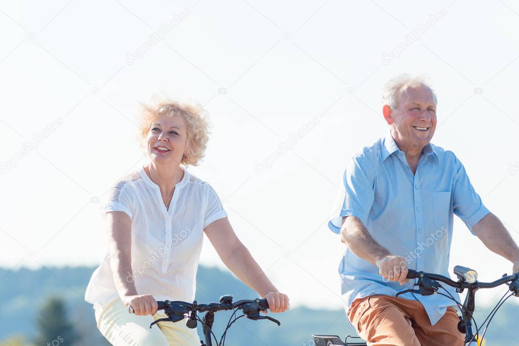 Active elderly couple riding bicycles together in the countryside