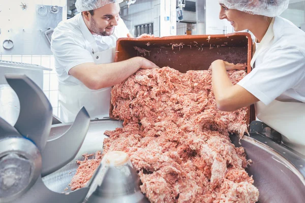 Team of butchers taking minded meat out of grinder — Stock Photo, Image