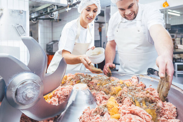 Butchers putting spices in minced meat