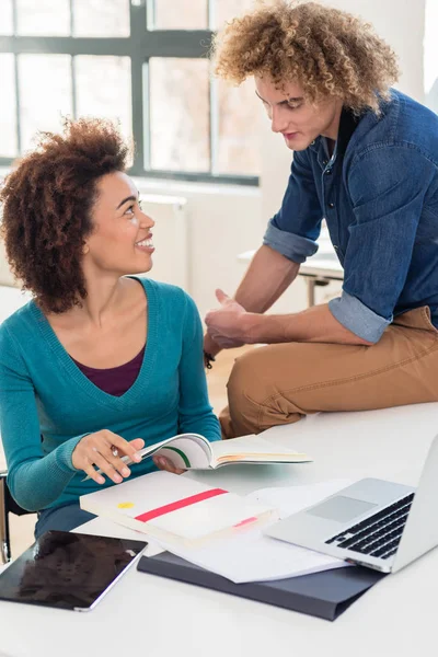 Two friendly classmates of different nationalities talking about a textbook — Stock Photo, Image