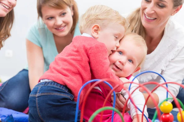 Groep gelukkige jonge moeders hun leuke en gezonde baby's spelen kijken — Stockfoto