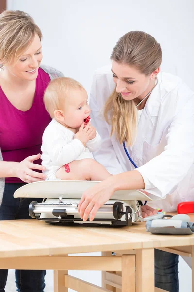 Specjalisty opieki pediatrycznej uśmiechający się podczas pomiaru wagi baby girl — Zdjęcie stockowe