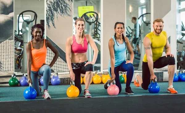 Four young people holding kettlebells during functional training — Stock Photo, Image