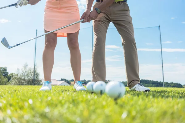 Low section of man and woman holding iron clubs while practicing — Stock Photo, Image