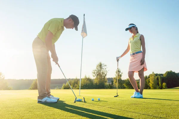 Férfi kész arra, hogy a hit a golf labdát a játék társa edzés közben — Stock Fotó