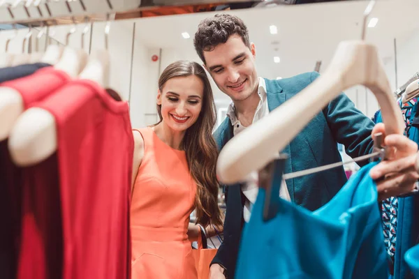Casal verificando os recém-chegados na boutique de moda — Fotografia de Stock