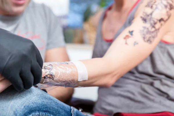 Close-up van de verpakte onderarm van een jonge vrouw na het krijgen van een tattoo — Stockfoto