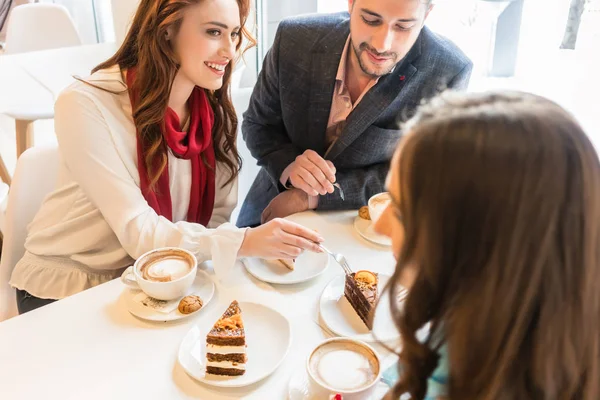 Šťastný pár sedí u stolu s jejich společného přítele v módní kavárně — Stock fotografie