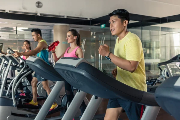 Bela mulher bebendo água durante o treinamento cardio em um ginásio na moda — Fotografia de Stock