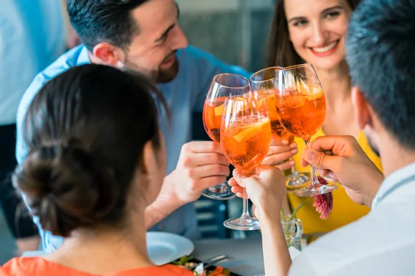 Cuatro amigos brindando juntos con una bebida alcohólica refrescante fría —  Fotos de Stock