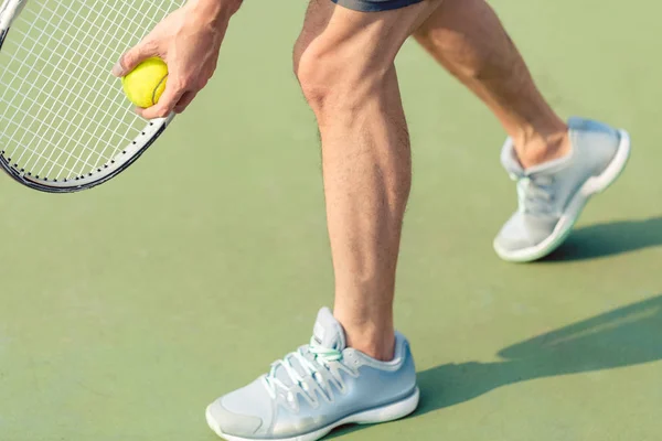 Profesyonel bir oyuncu topu ve tenis raket tutan düşük bölümü — Stok fotoğraf