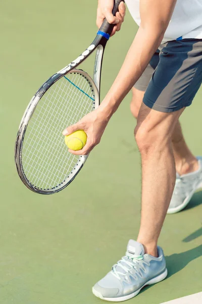 Низкая секция профессионального игрока, держащего мяч и теннисную ракетку — стоковое фото