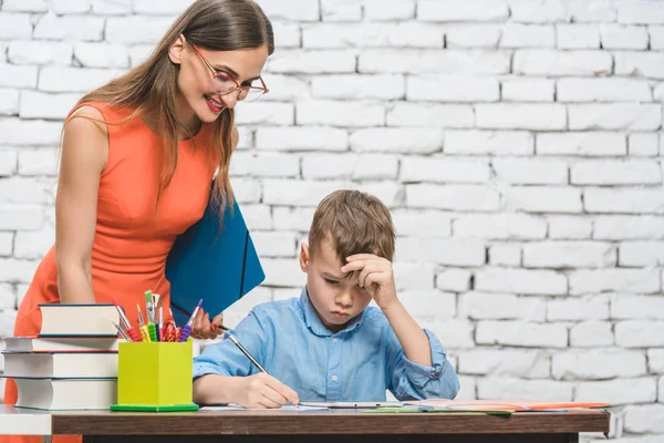 Studente ragazzo fare lavoro in scuola supervisionato da suo insegnante — Foto Stock