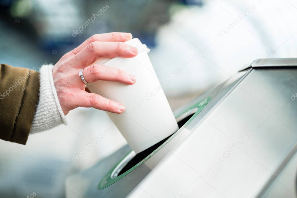 Woman using waste separation container throwing away coffee cup