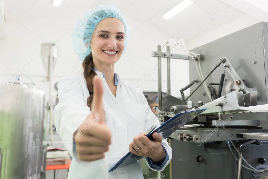 Portrait of happy woman manufacturing specialist showing thumbs up