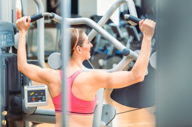 Tonda silah uygun bir kadınla görünümünü arka ve spor salonunda egzersiz geri