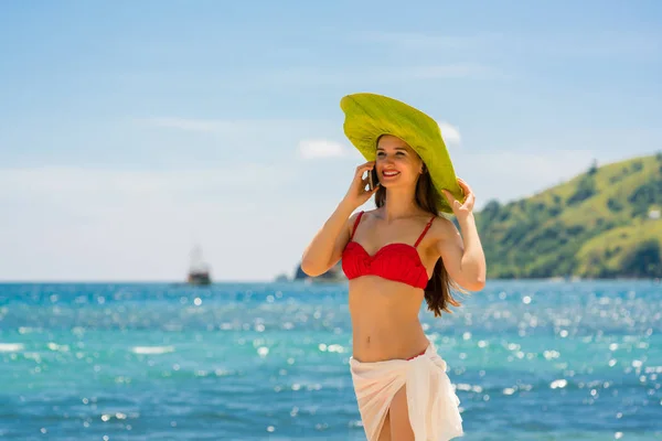 Jonge mooie vrouw die lacht tijdens het gesprek op een mobiele telefoon op het strand — Stockfoto