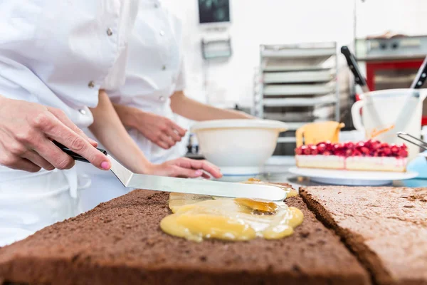 Confeiteiro mulher chegando bolo de chocolate pronto com cobertura — Fotografia de Stock