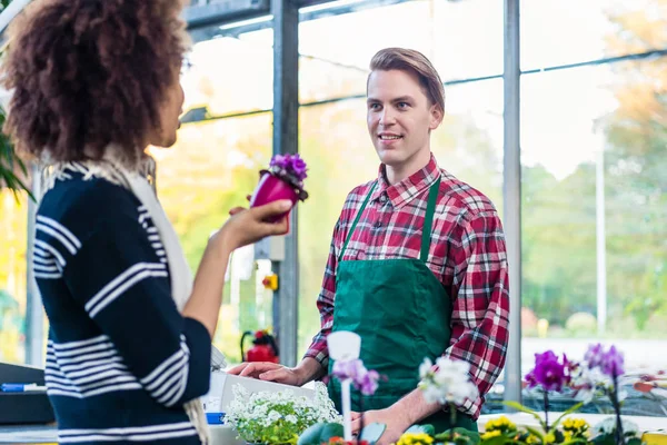 Schöner Mann, der einem Kunden zuhört, während er als Kassierer arbeitet — Stockfoto