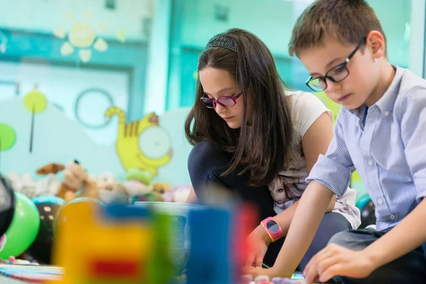 Jolie fille jouant à côté de son camarade de classe dans un jardin d'enfants moderne — Photo