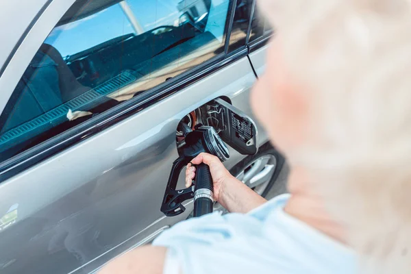 Närbild av en senior kvinna fylla upp bensintanken av hennes bil hand — Stockfoto