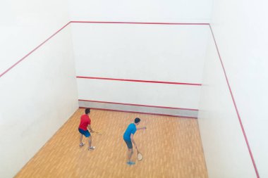 İki rekabetçi genç adamın squash oyun oynarken arka görünüm