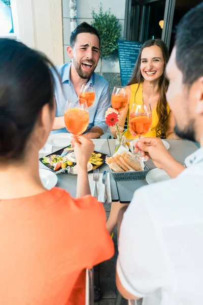 Twee gelukkige jonge paren roosteren tijdens de vergadering samen op restaurant — Stockfoto