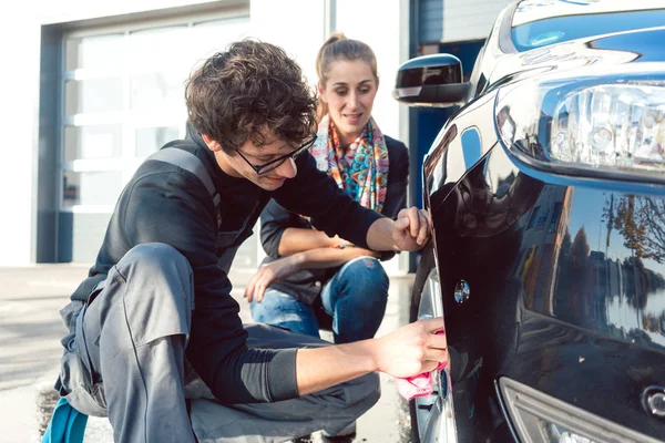 Homem ajudando mulher limpeza jantes em lavagem de carro — Fotografia de Stock