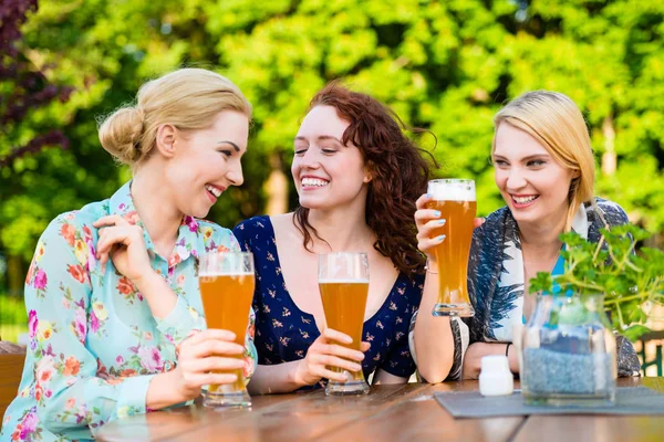 Vänner skålar med öl i trädgården pub — Stockfoto