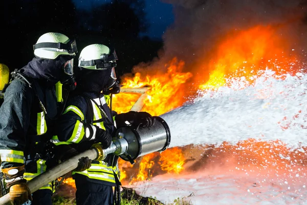 Πυροσβέστες Πυροσβέστες Που Σβήνουν Μια Μεγάλη Φλόγα Στέκονται Προστατευτική Φθορά — Φωτογραφία Αρχείου