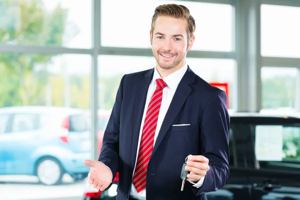 Young man or auto dealer in car dealership — Stock Photo, Image
