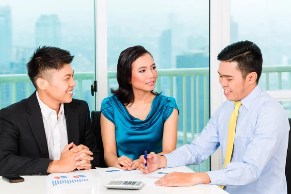 Asian banker selling insurance to couple — Stock Photo, Image