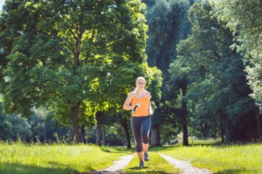 Genç kız bir yola doğru ağırlık Dambıl ile çayır üzerinde çalışan