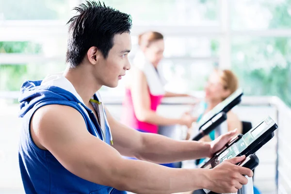 Hombre deportivo en la cinta de correr coqueteando con chicas sonrientes — Foto de Stock