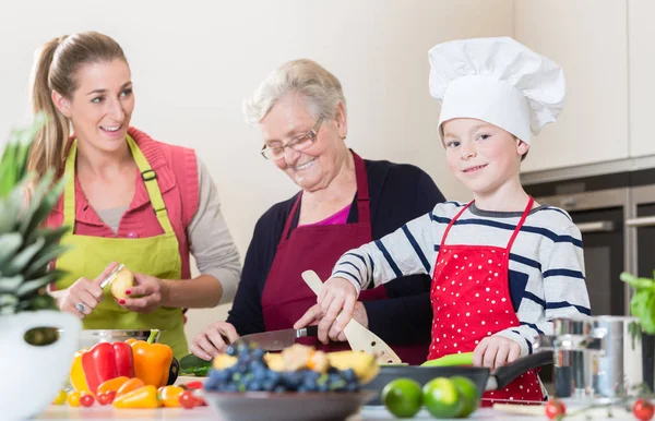 Abuela, mamá e hijo hablando mientras cocinan en la cocina — Foto de Stock