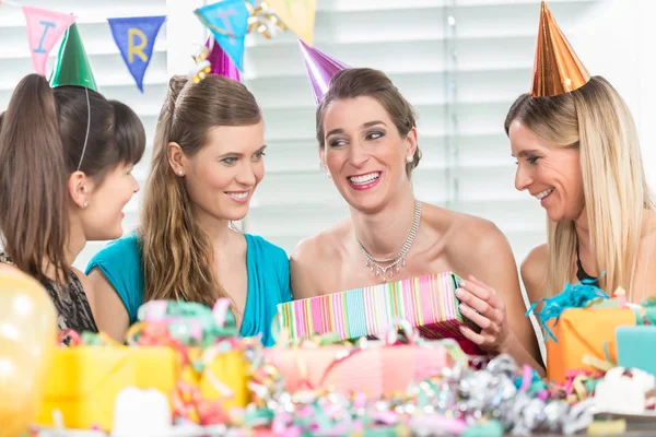 Glad kvinna som håller en presentbox under en överraskning födelsedagsfest — Stockfoto