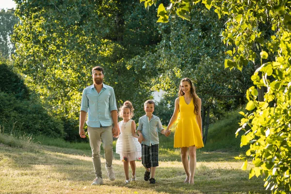 Lycklig familj med två barn hålla händerna under fritids promenad — Stockfoto