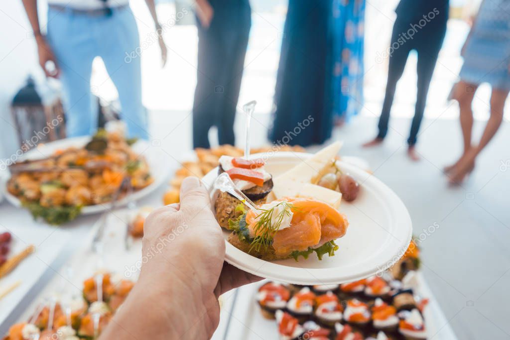 Man helping himself on Buffet of party outdoors taking food 