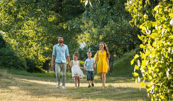 Щаслива сім'я з двома дітьми тримає руки під час прогулянки — стокове фото