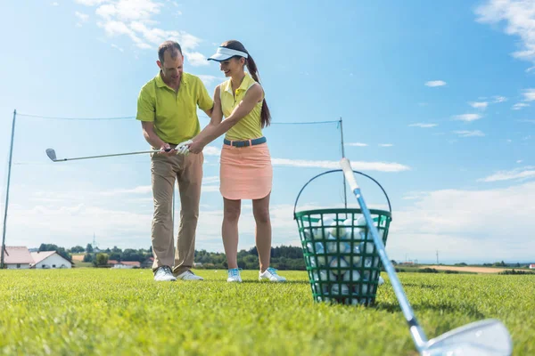 Cheerful young woman learning the correct grip and move for using the golf club — Stock Photo, Image