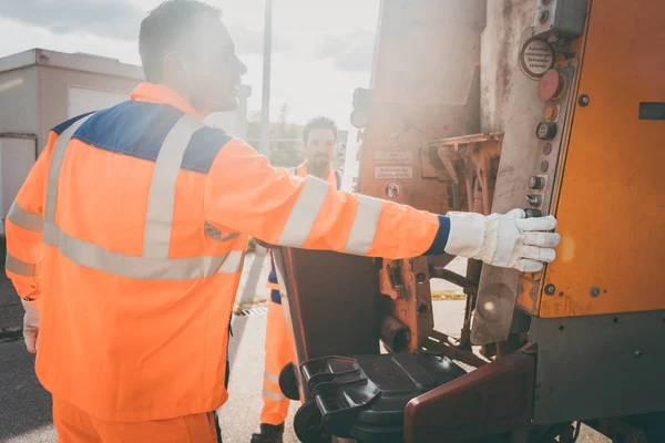 Zwei Mitarbeiter der Müllabfuhr laden Müll in Müllwagen — Stockfoto