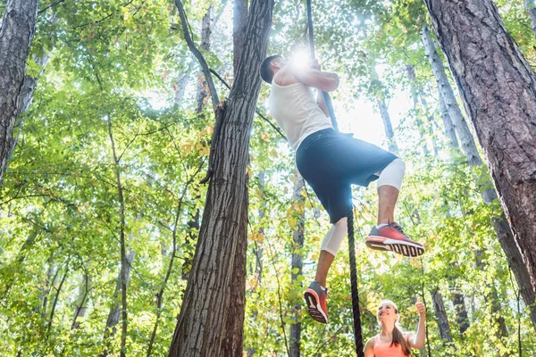 Homem e mulher escalando corda para o esporte na floresta — Fotografia de Stock