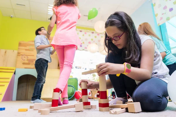 Linda chica construyendo una estructura en equilibrio durante el tiempo de juego en el jardín de infantes —  Fotos de Stock